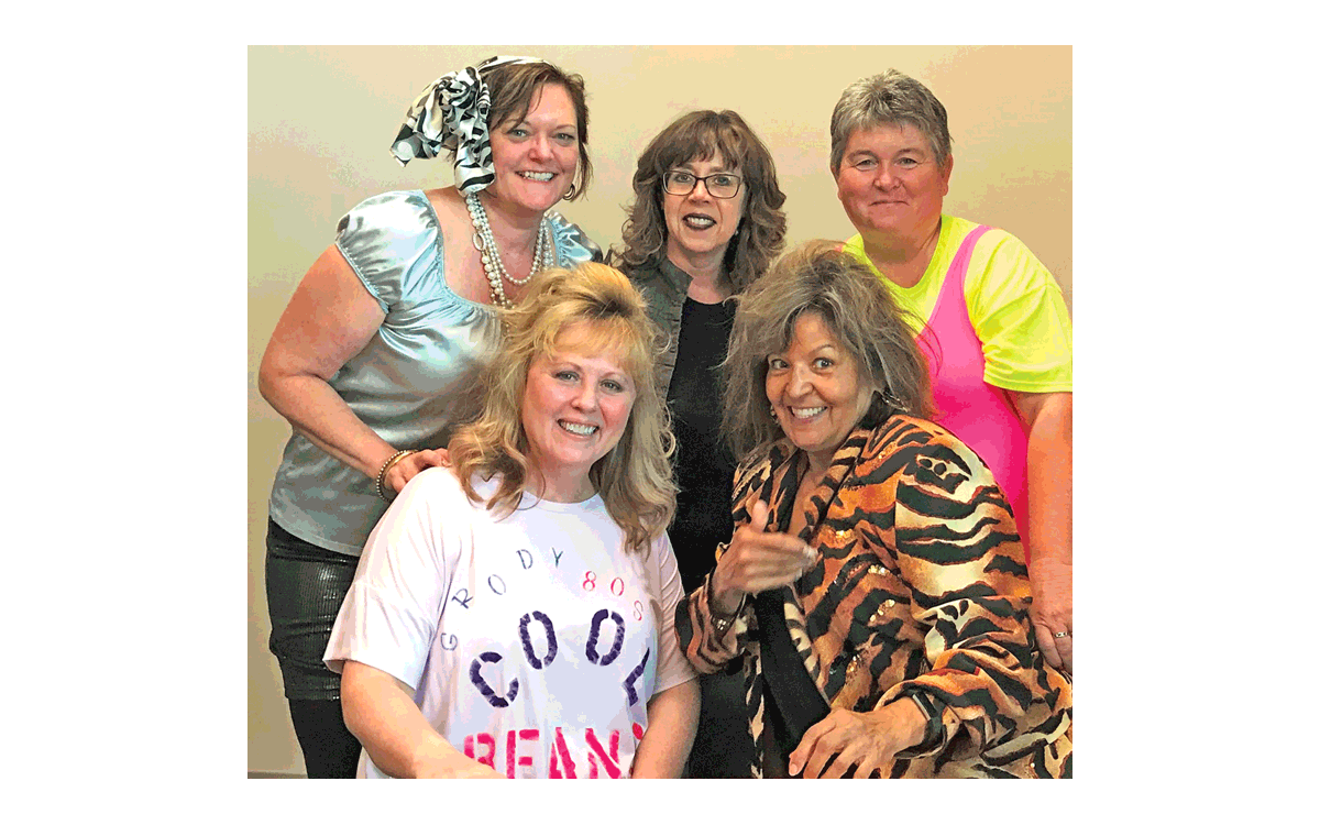 Library staff members and volunteers are dressed in their 1980s garb and ready for the Back to the 1980s BBQ Bash party! Clockwise from top left: Brenda Blough, Aurora Public Library (APL) human resources manager; Michaela Haberkern, APL deputy director; Kelly McCleary, Aurora Foundation Board president; Dee Basile, Library Board member and Foundation Board vice president; and Laura Stoney, Foundation manager. Submitted photo