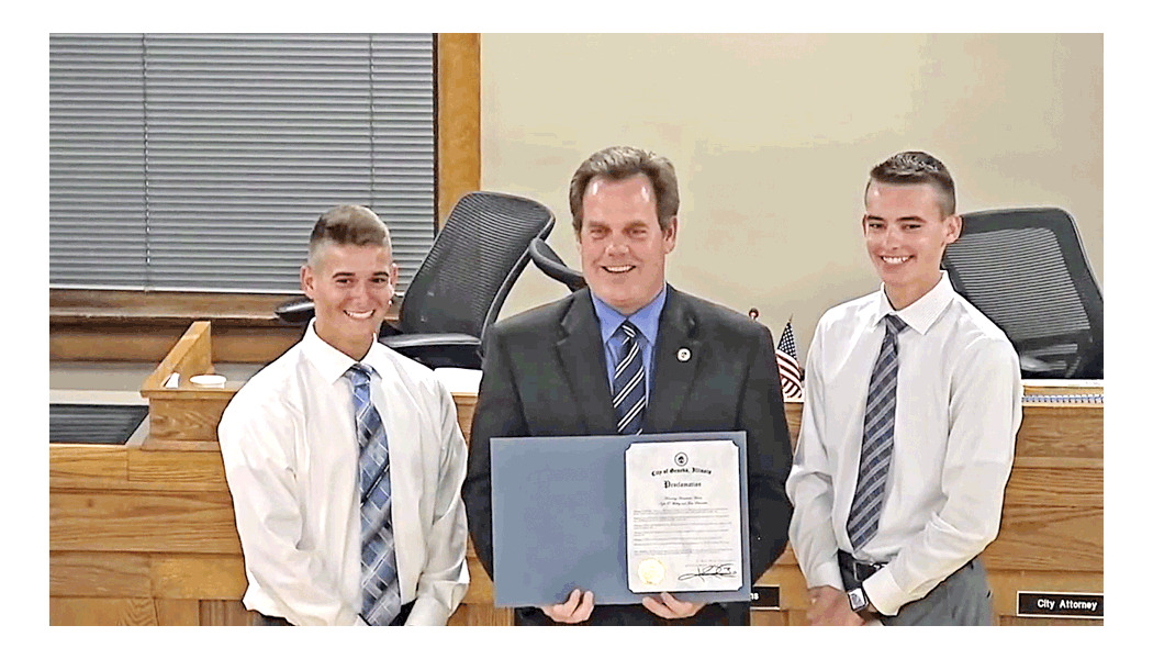 Heroism rewarded: The Geneva City Council honors Geneva teens John Schneider, left, and Kyle O'Malley Monday for heroism. Geneva mayor Kevin Burns holds the certificate. The young men helped save a woman's life after a fire-filled car crash on Interstate-88 August 11. Schneider is a student at Geneva High School. O'Malley is a 2018 graduate of the school. Both are in cadet training in Geneva to be police officers. They were lead stories on Chicago television news. City government of Geneva photo