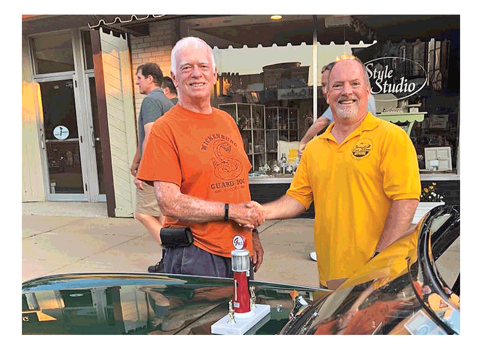 Jim McWethy of Downers Grove, left, receives congratulations from a Summer Nights Classic Car Show official Friday for Best in Show in Downers Grove.