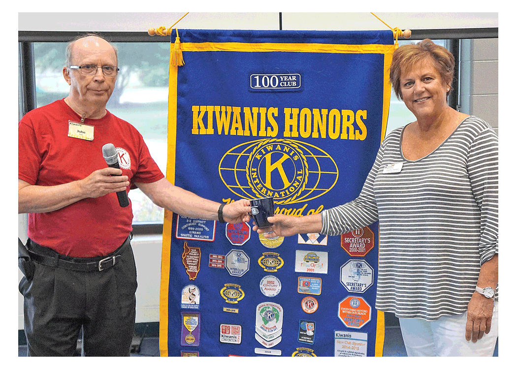 John Ross, president of Kiwanis Club of Aurora, presents a Kiwanis coffee mug to Cathy Ferrel, Marie Wilkinson Food Pantry’s East Pantry coordinator