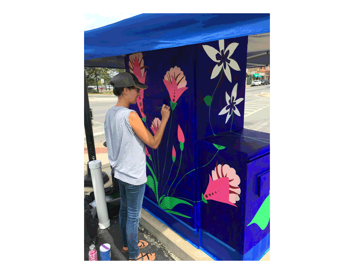 Laura Lynne, a mural designer, paints a utility box in Aurora at the corner of New York and River Streets. Several other artists are working on various utility boxes downtown.