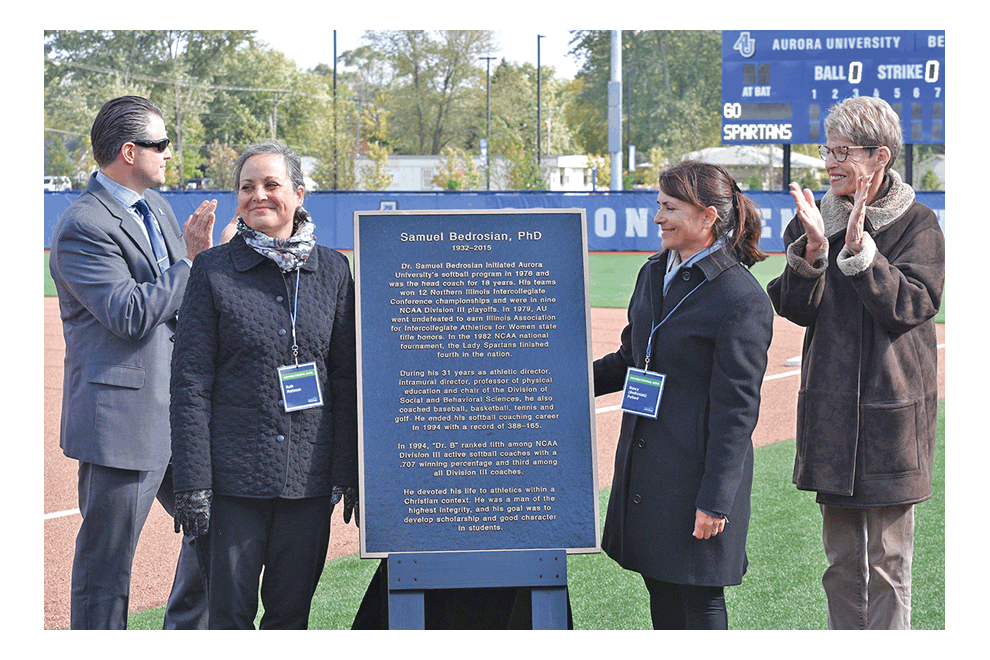 Jim Hamad, Aurora University athletic director, left; Ruth Bedrosian Matteson; Nancy Bedrosian Pollard; and Hillary Brennan; Aurora University trustee, unveil plaque at Samuel Bedrosian Softball Stadium dedication Saturday at Edgelawn Drive and Jericho Road. The late Bedrosian initiated the University’s softball program, was head coach for 18 years, his teams won 12 conference championships, and he was athletic director for 31 years. Over the weekend the school announced it would build a baseball field at the complex. Sylvia Springer/Aurora University photo