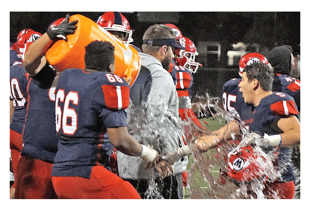 West Aurora High School head football coach Nate Eimer receives a container of liquid in the celebration Saturday evening from players following a 28-20 victory over visiting South Elgin.