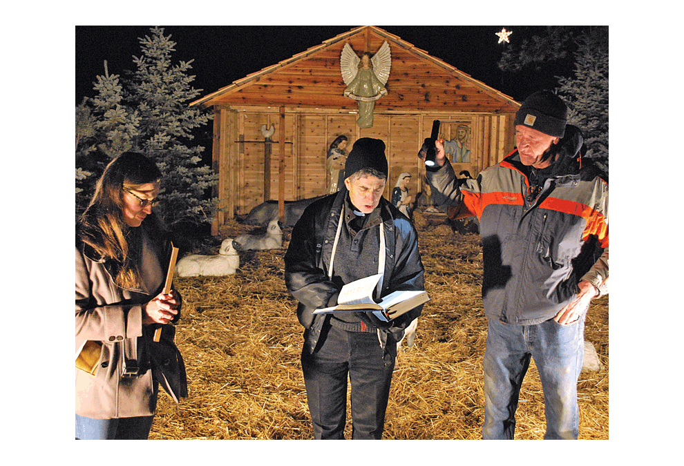 The 67th year of Lehnertz Avenue Christmas display receives a blessing of the crib Sunday in Aurora from Father Jerome Leake of St. Joseph’s Parish. The Nativity scene and lights and information on houses and property is a tradition in the community. Jason Crane/The Voice