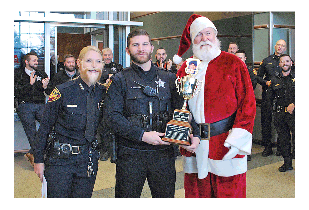 Best beard: Tyler Reeder shows the biggest trophy in the Aurora Police Department “No Shave November” Contest to raise money for pancreatic cancer. He stands between Kristen Ziman, police chief and Santa. See page 17. See face book.com/thevoice.us. Jason Crane/The Voice