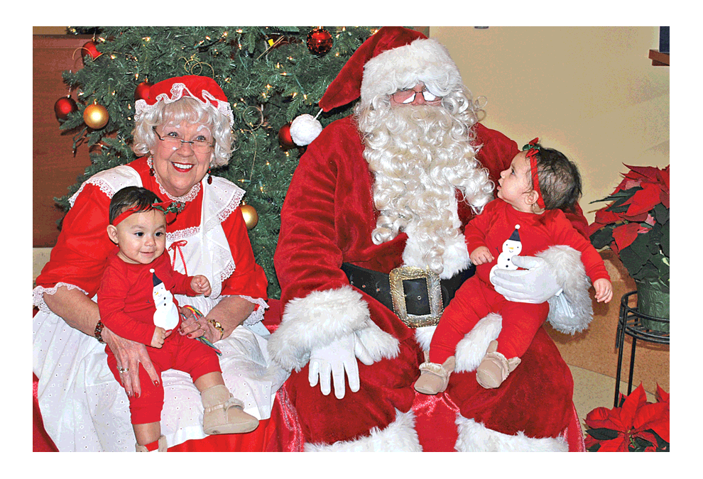 Mrs. Claus and Santa Claus visit the Montgomery tree-lighting Sunday evening and find twins on their laps, Thalia and Camila Bustamante. Jason Crane/The Voice