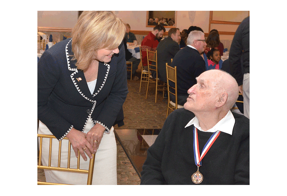 Everett Schlegel of Elgin, a Pearl Harbor attack (December 7, 1941) survivor, is greeted by Jeanne Ive, Ill State representative, 42nd District, at the annual Pearl Harbor Day luncheon Monday at Gaslite Manor Banquets in Aurora. Ives, an Army veteran, was the keynote speaker at the luncheon sponsored by Aurora Navy League Council 247. For the first time, World War II veterans were honored at the event. Al Benson/The Voice