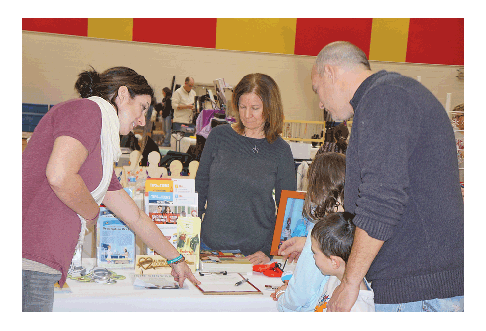Jennifer Flory, left, points to information at the Holiday in the Grove in Sugar Grove Saturday on her Alison Flory Foundation. The event at the Kaneland John Shields Elementary School was a part of Sugar Grove’s holiday celebration. Carter Crane/The Voice