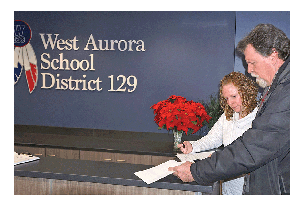 James Buzzard turns in nearly 2,400 petition signatures (see inset above) recently to Joy Engfer, West Aurora District 129 School Board secretary, for placement of an advisory referendum on the April 2 consolidated election ballot in Kane County on the subject of the Aurora Public Library West Branch’s future. Right, Joy Engfer turns in the signatures to the Kane County Clerk’s facility on Downer Place in Aurora. Buzzard led the drive to collect signatures. The West Aurora School Board’s deadline to turn in the request to Kane County is Jan- uary 24. Carter Crane/The Voice