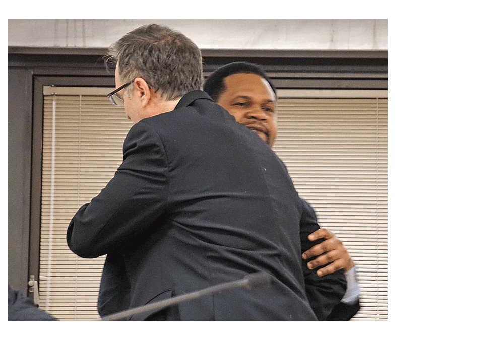 Mayor Richard Irvin, of Aurora, right, gives a quick hug to Judd Lofchie, alderman of Aurora’s 10th Ward during the Aurora City Council meeting Tuesday. Mayor Irvin had received criticism in a letter from a constituent following the last City Council meeting. He read the letter which discribed Irvin’s actions as disrespectful. He apologized to Lofchie and to the City Council. Jason Crane/The Voice