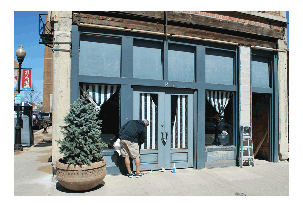 Ice cream dreams by Fourth of July: Workers clean the windows of the former Aurora Silverplate Manufacturing building in downtown Aurora at 6 E. Downer Place. The building is being restored and a planned ice cream shop has a target date to open by the Fourth of July. The site has been vacant for many years. Jason Crane/The Voice
