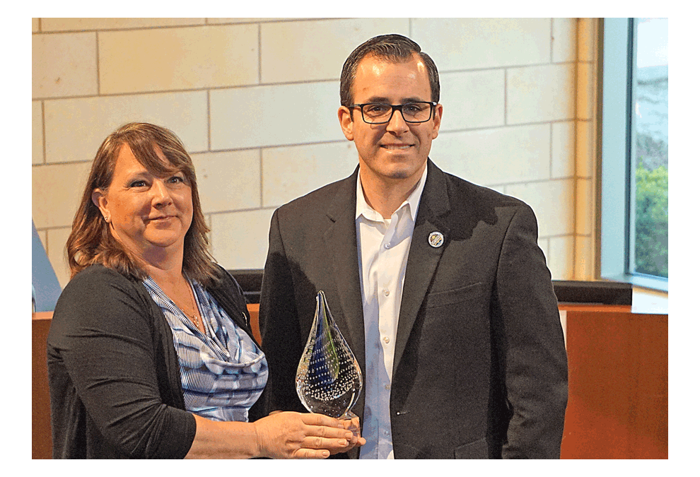 Laurie Frieders, executive director of the Illinois Water Environment Association (IWEA), presents the 2019 Public Official Award to Montgomery Village president Matt Brolley at the Village Board meeting Monday. The award is given to a public official who has documented significant contributions in clean water legislation, public policy, government service, or another area of public prominence that results in improvements to the water environment. Frieders said Brolley was nominated because the Village of Montgomery has several environment-friendly policies.