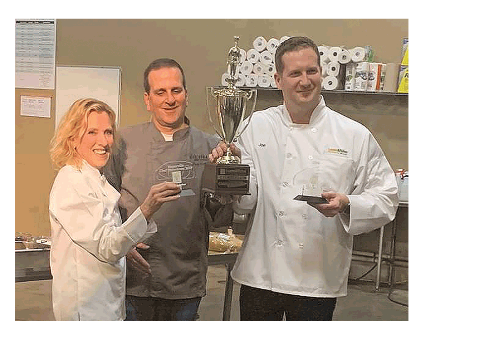 Naperville Chef Showdown: Chef Mark Grimes, middle, holds a trophy after Che Figata was announced the winner of the Loaves & Fishes’ second annual Naperville Chef Showdown fundraiser, Wednesday, April 17 in Naperville. The competition was between two teams led by chef Crispin Plata from Mesón Sabika and chef Grimes from Che Figata. The sold-out event supports Loaves & Fishes Community Services. Left to right, Loaves & Fishes Board member Dr. Laura Bokar, Fox Valley Institute; chef Mark Grimes, Che Figata; Loaves & Fishes Board member Joe Chura, Dealer Inspire. Runner-up was Meson Sabika, chef Crispin Plata. Loaves & Fishes Community Services